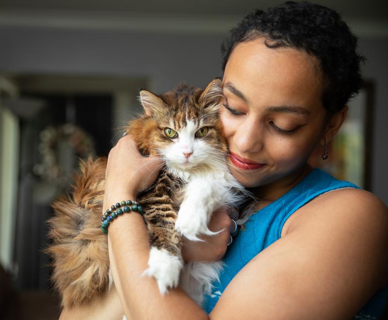 Person cradling a brown and white tabby cat in her arms