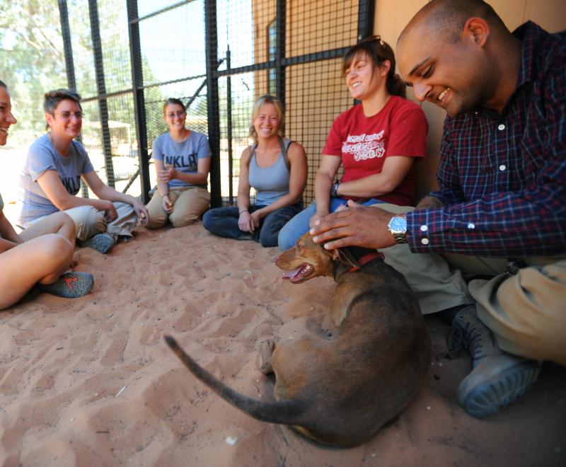 Group of smiling people sitting with a dog in sandy area in Utah desert