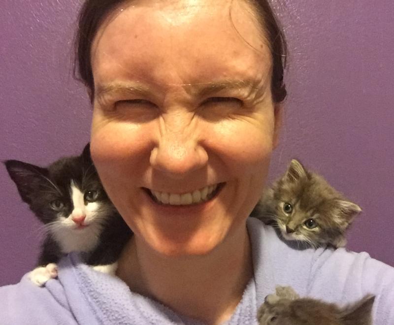 Lizel Allen laughing with a kitten on each of her shoulders