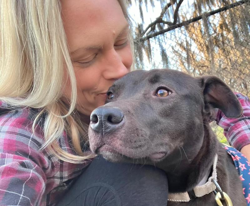 Person kissing the head of Delilah the dog