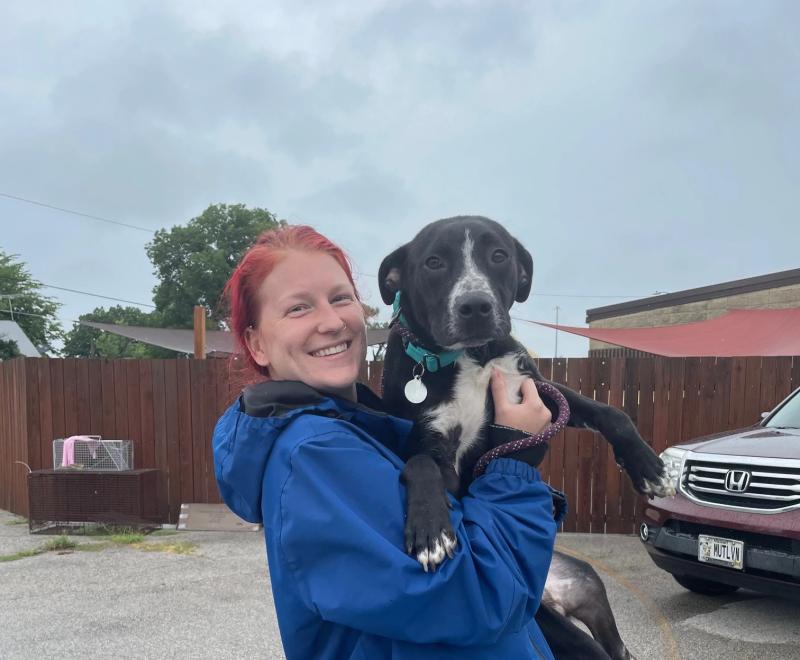 Smiling person holding a dog rescued from a flood