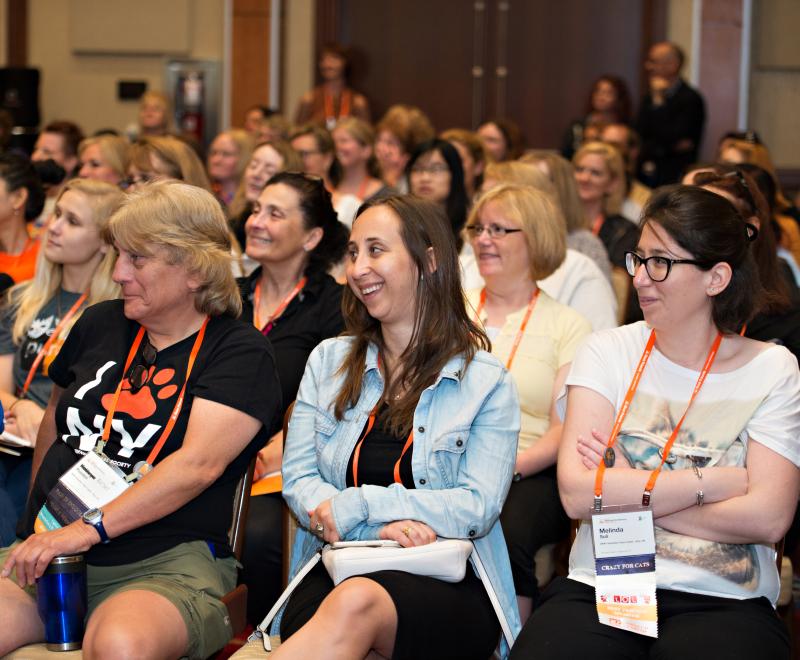 Smiling crowd listening to a person speak