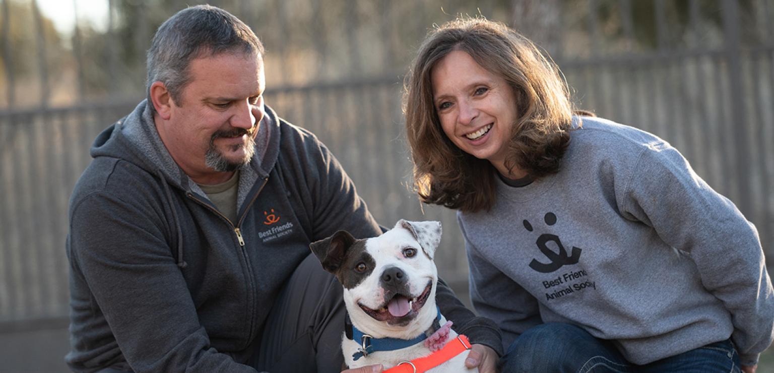 Bella the dog, very happy, between her adopters