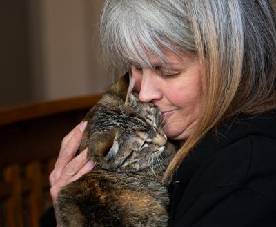 Person holding and snuggling with a torbie cat