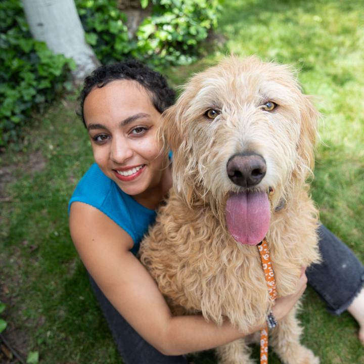 Woman cuddling with fluffy dog on lawn