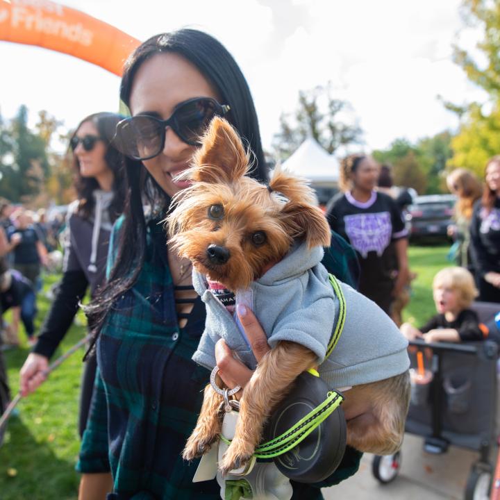 Smiling person holding a small dog at Strut Your Mutt