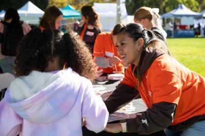 Volunteer wearing an orange Best Friends T-shirt helping a child