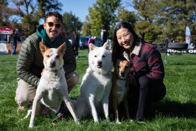 Two people posing with three dogs at Strut Your Mutt