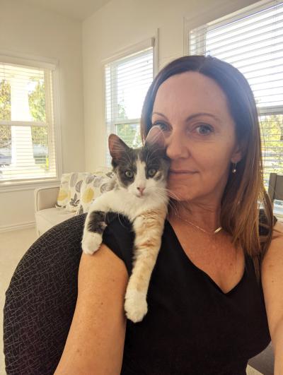 Smiling person holding Blueberry the cat in front of some windows