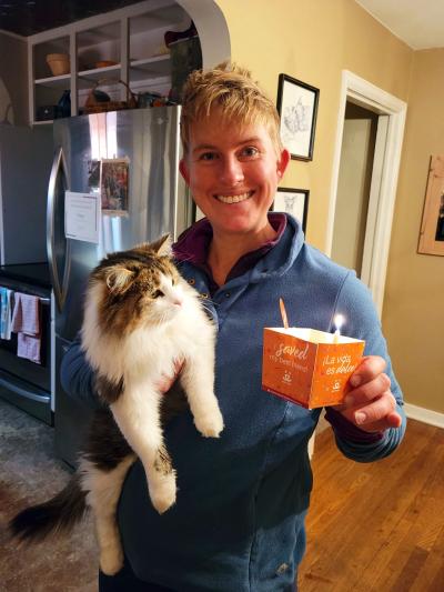 Dolly Parton the cat being held by her smiling adopter, who is holding an adoption celebration cat in the other hand