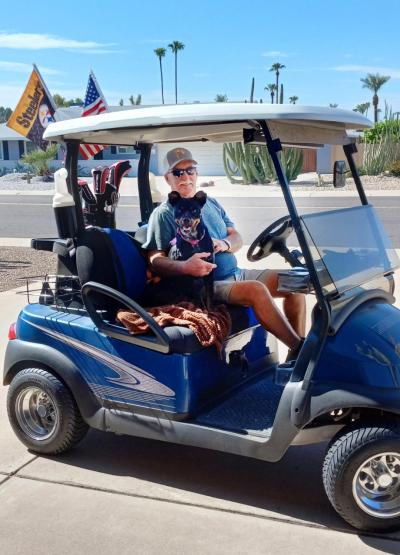 Person holding EllyRose the dog in a golf cart