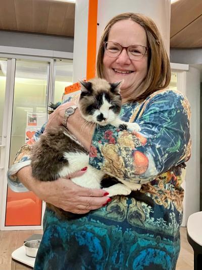 Cinderella the cat being held by her smiling adopter