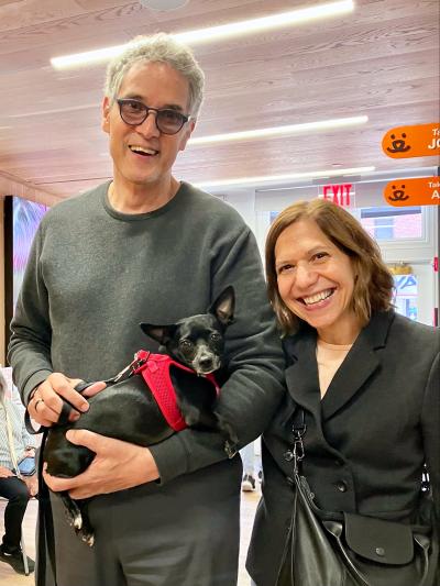 Smiling couple holding small black dog Mimi