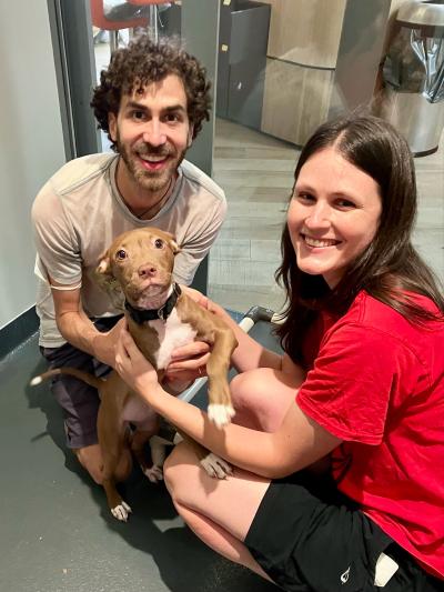 Jamie and Brian smiling and holding Olive the puppy