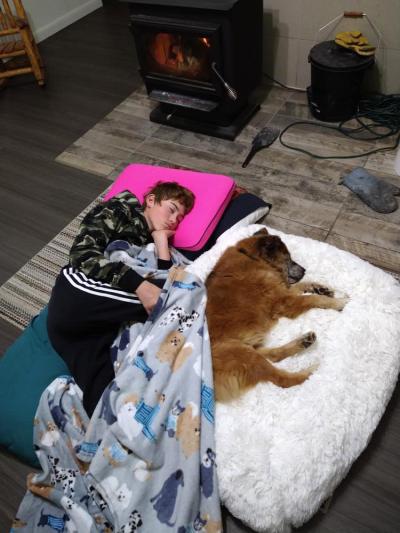 Kid sleeping on the floor (on pillows) next to Rusty the dog