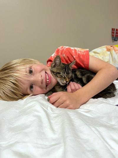 Beck lying down and snuggling with Leopard the kitten