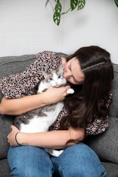 Person sitting on couch hugging Zoey the cat