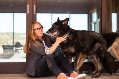 Julie Castle sitting on the floor holding Shadow the German shepherd