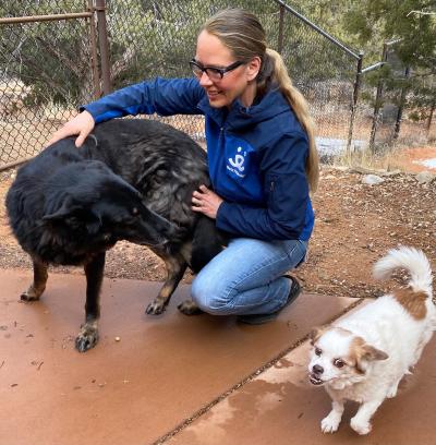 Julie Castle petting Shadow the German shepherd, with another smaller dog beside them