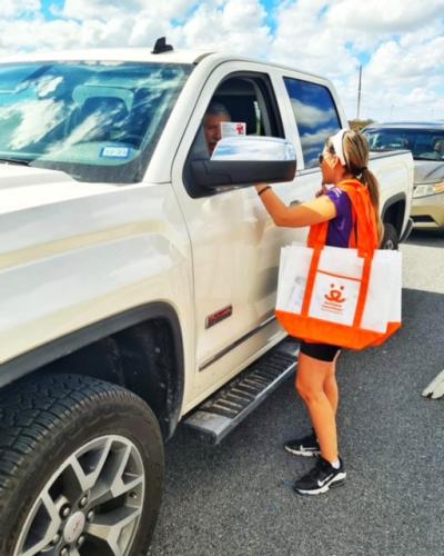 Person with a Best Friends logo bag talking to a person in the driver's seat of a large white truck