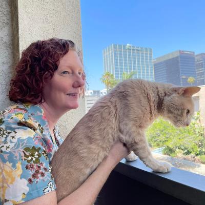 Person holding Banjo the cat by a window with building outside