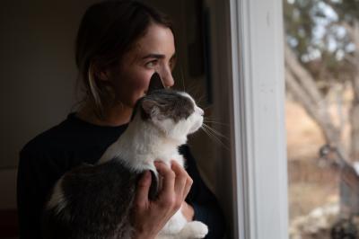 Catey holding Adonis the cat beside a window