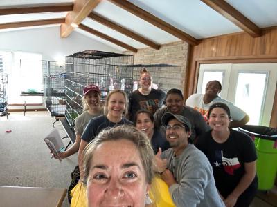 Selfie featuring the group of people from Best Friends helping with the cats, with wire kennels behind them