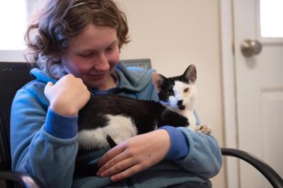 Kairuku the kitten being held in a person's arms