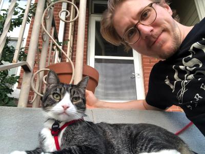 Sam DeMastrie  with Tigger the cat outside on a leash