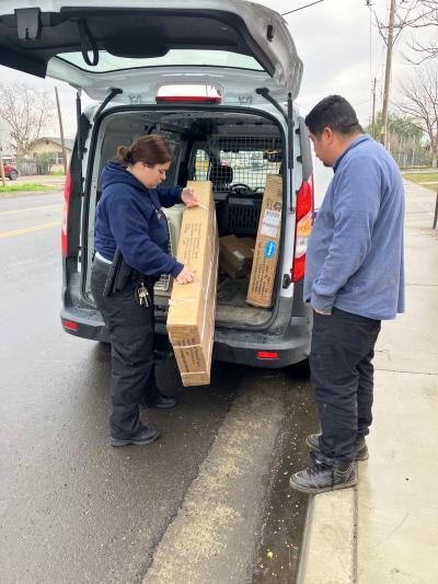 Officer Liset Moreno unloading a dog house from a vehicle to give to a man