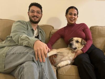 Gilda the dog lying on a couch between her adopters