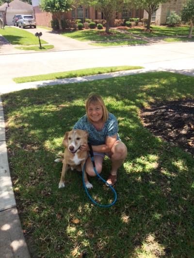 Smiling person and Fergus the dog outside on a lawn in the shad of a tree