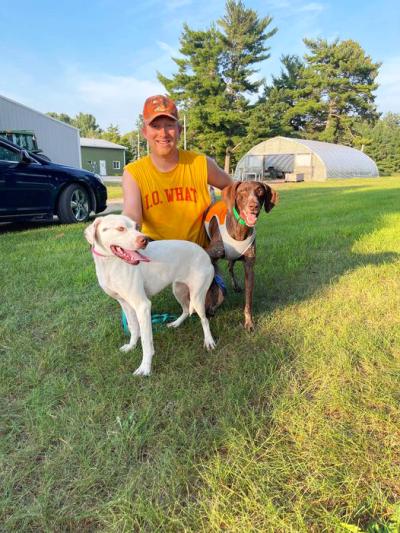 Callie the dog with her new family (a person and another dog) outside on the grass