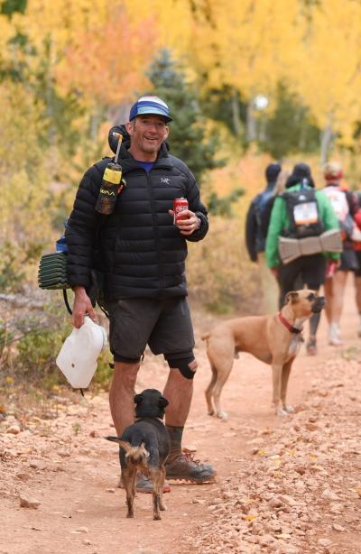 Bart Battista outside with other people and dogs with fall foliage in the background