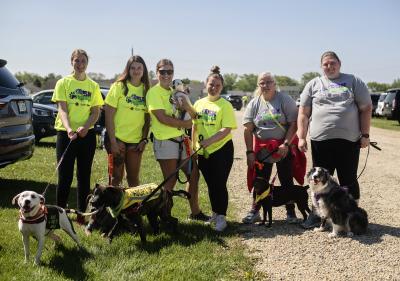 Group of people outside walking dogs and one holding a puppy