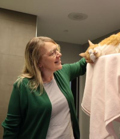 Smiling person petting an orange and white cat