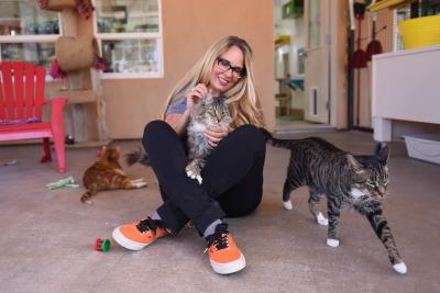 Best Friends CEO Julie Castle sitting on the floor with a cat in her lap and other cats around her