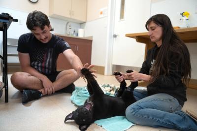 Sweet Baby James lying upside-down on the floor with two people holding his feet up as part of physical therapy 