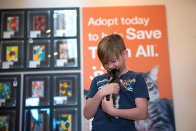 Volunteer holding Arabelle the kitten in front of a sign