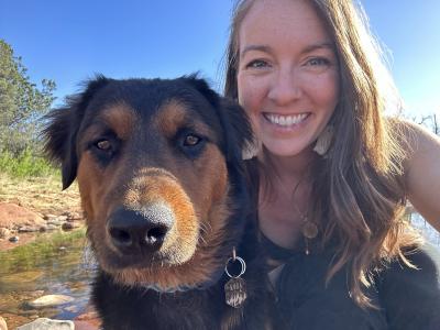 Selfie of Koda the dog and his person while outside with water and a blue sky behind them