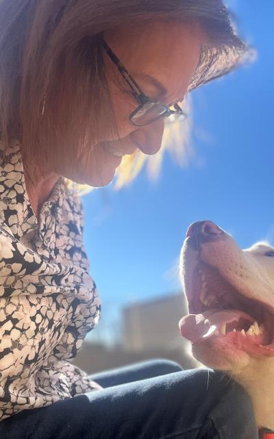 Lorie Comer looking down happily at a dog