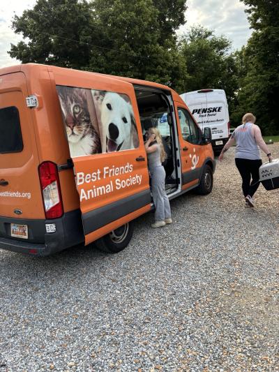 The Best Friends transport van with a couple people, one who is carrying a carrier with a cat