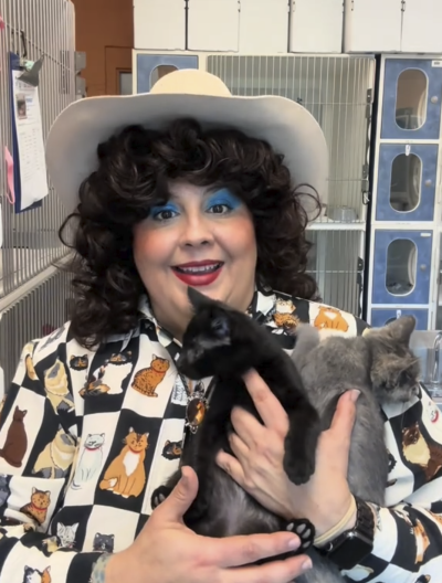 Volunteer Anita Walker dressed up in country western gear holding George and Little Miss Muffet the kittens