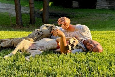 Steward the dog lying in the grass with his adopter