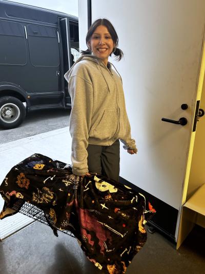 Smiling person holding a covered live trap containing a cat