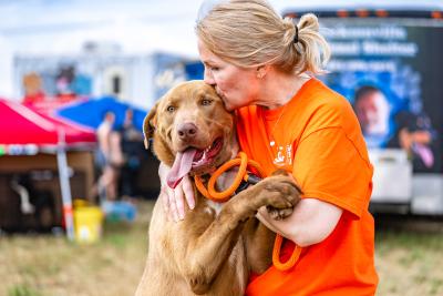 Person kissing a large brown dog at the Best Friends Super Adoption in Northwest Arkansas