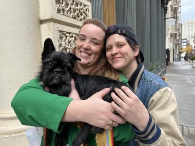 La Bamba the dog being held by his smiling adopters