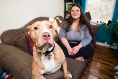 Smiling person relaxing on a couch with a big dog