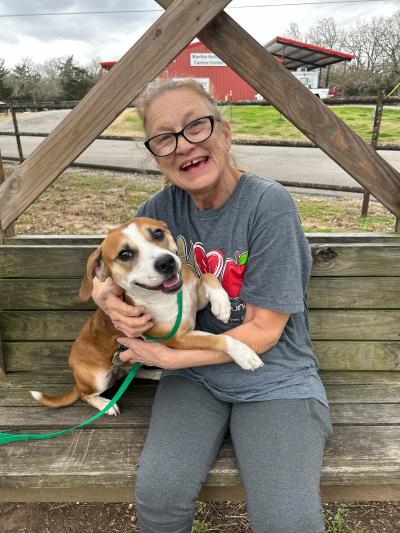 Smiling person outside on a bench hugging a happy dog in her arms