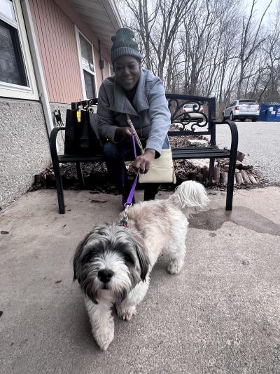 Person sitting outside on a bench holding a fluffy dog on a leash